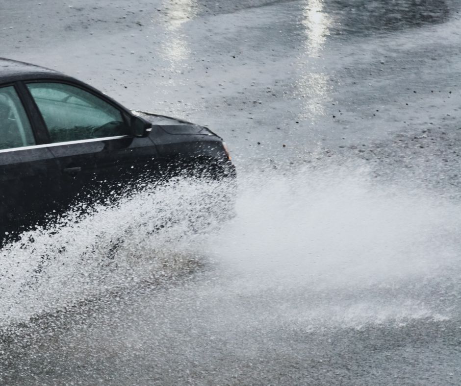 A car splashing through a rainy road.
